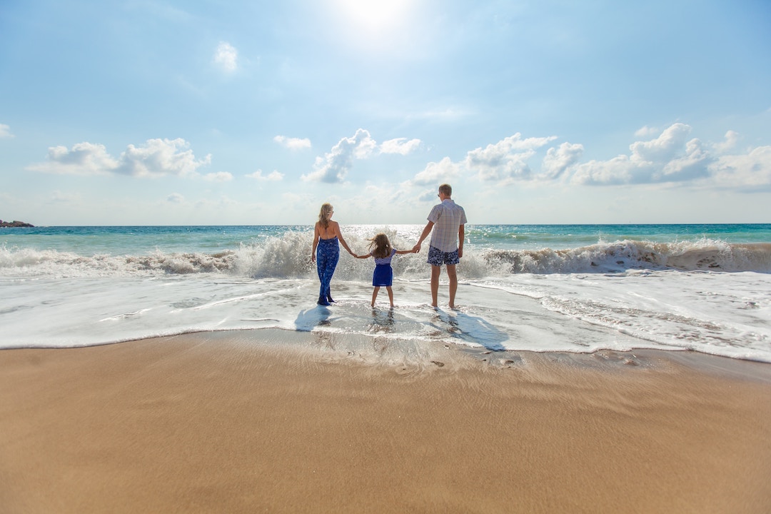 עצמאות כלכלית - זוג עומד על חוף הים מביט לעבר האופק עם ילדם הקטן לאחר פרישה מוקדמת וחופש כלכלי